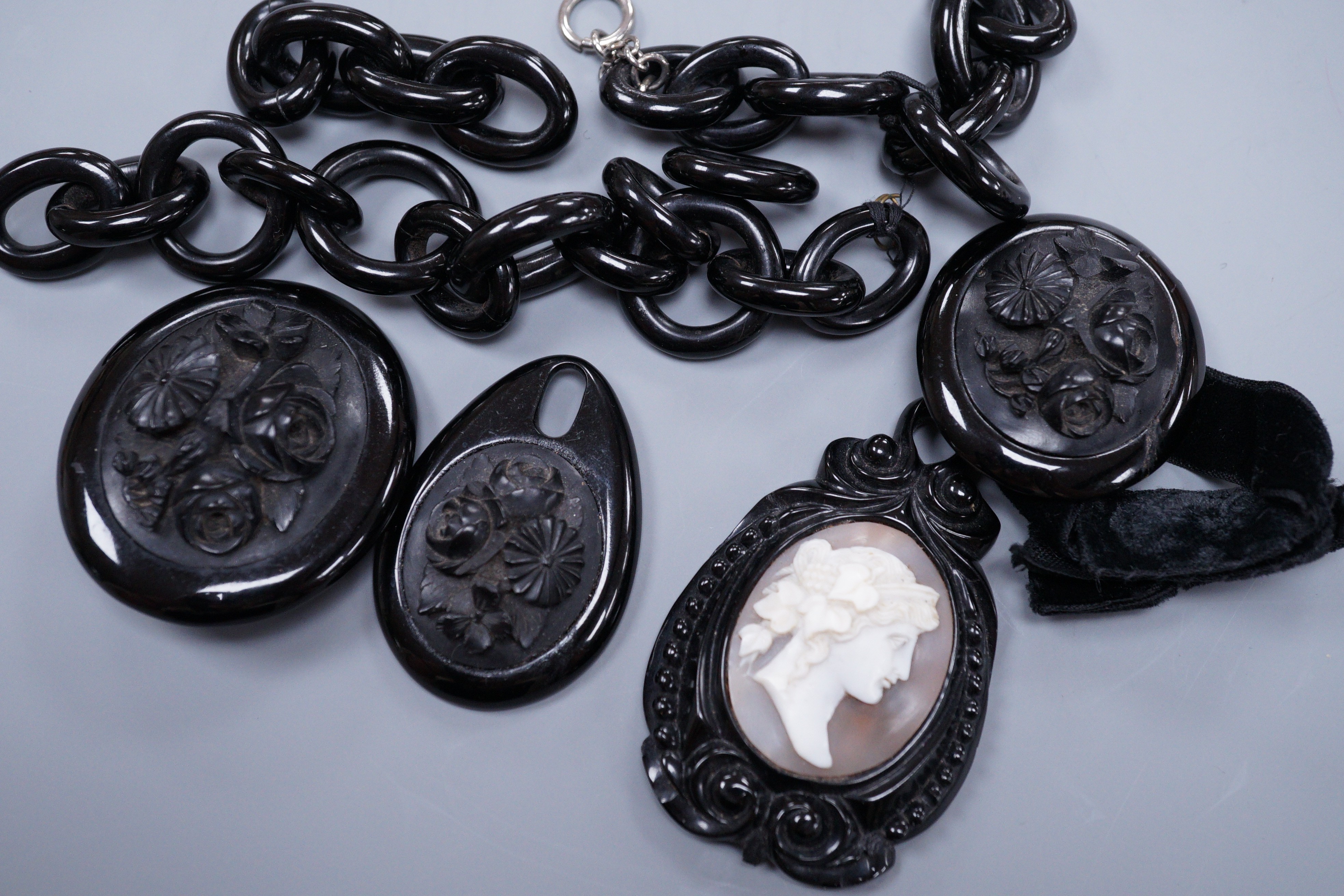 A Victorian floral carved jet brooch with matching bracelet and incomplete chain necklace and a similar pendant inset with a cameo